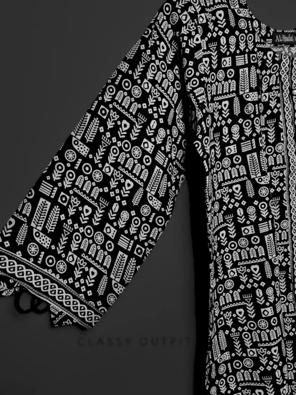 A black and white robe hanging on a clothes hanger, featuring a detailed pattern, displayed indoors.