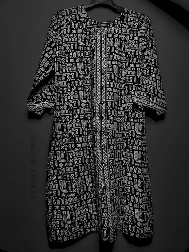 A black and white robe hanging on a clothes hanger, featuring a detailed pattern, displayed indoors.