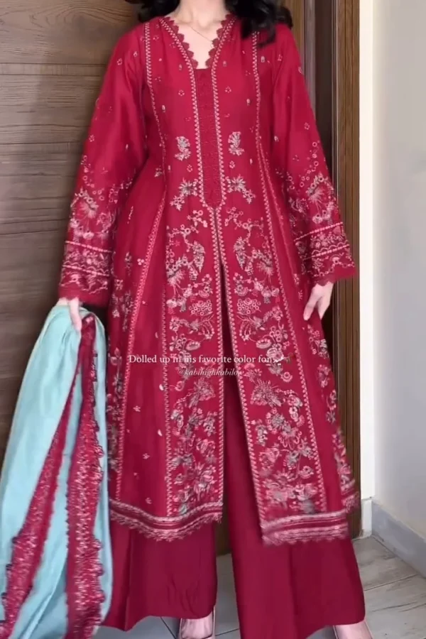 Woman wearing a deep red embroidered traditional outfit consisting of a long kameez adorned with intricate floral patterns in white and silver thread. The design extends along the sleeves and front panels. She pairs it with matching wide-legged pants and holds a light mint green dupatta with red embroidered trim. The outfit has a scalloped neckline and ornate sleeve cuffs, styled for a festive or formal occasion. Let me know if you need a shorter version or want this adapted for Instagram captions, product listings, or accessibility purposes!
