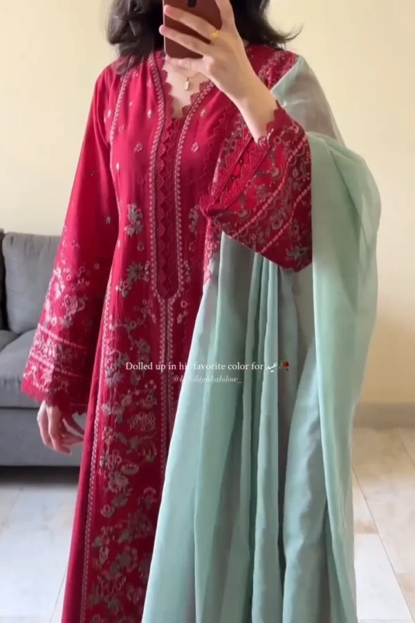 The outfit in the image is a traditional South Asian ensemble, likely a shalwar kameez. Here’s a description: Top (Kameez): The kameez is a rich crimson red with detailed embroidery in shades of gold, silver, and deep red. The embroidery features floral and vine patterns, especially concentrated around the neckline, sleeves, and front panel. The neckline is scalloped with intricate lace-like detailing. Dupatta: A contrasting light mint or pastel green chiffon dupatta is draped over one shoulder, adding a soft, elegant balance to the bold red outfit. Styling: The person is accessorizing minimally with a gold ring and a delicate pendant necklace, letting the outfit remain the focal point. This outfit would be ideal for festive occasions like Eid or weddings, blending tradition with elegance. Would you like a caption, alt text, or styling suggestions for this outfit?